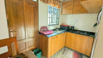 A compact kitchen with wooden cabinets, a sink, a microwave, and a stove.