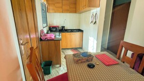 A compact kitchen with wooden cabinets, a microwave, and a gas stove. - Zebra Nest Apartpment (Kilimanjaro Region)