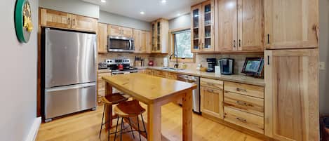 A modern kitchen with wooden cabinets, stainless steel appliances, and a central island with stools.