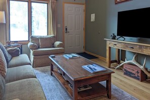 Ein Wohnzimmer mit einer Couch, einem Couchtisch, einem Fernseher und einer Tür.