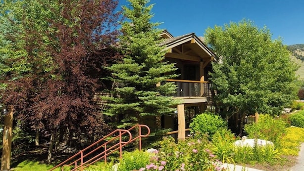 A lodge with a wooden exterior, a balcony, and a surrounding garden with various plants and trees. - Quaint mountain condo w/two fireplaces, mountain views, balcony & great location (Jackson)