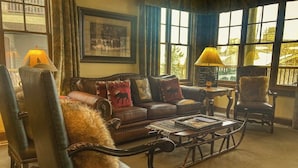A cozy living room with a leather sofa, a coffee table, and two lamps. - Quaint mountain condo w/two fireplaces, mountain views, balcony & great location (Jackson)