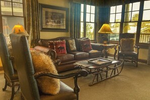A cozy living room with a leather sofa, a coffee table, and two lamps. - Quaint mountain condo w/two fireplaces, mountain views, balcony & great location (Jackson)