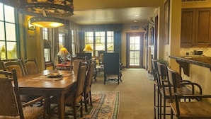 A dining area with a long table, chairs, and a patterned rug. - Quaint mountain condo w/two fireplaces, mountain views, balcony & great location (Jackson)
