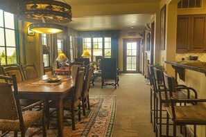 A dining area with a long table, chairs, and a patterned rug. - Quaint mountain condo w/two fireplaces, mountain views, balcony & great location (Jackson)