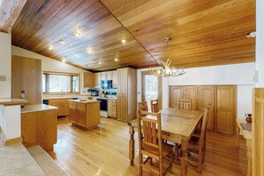 Eine geräumige Küche mit Holzausstattung, einem Esstisch und einer Chandelier.