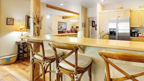 Une cuisine avec des chaises en bois, un réfrigérateur et une table à manger.