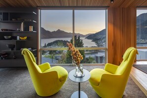 Ein modernes Zimmer mit großem Fenster, zwei gelben Stühlen, einem kleinen Tisch und einer Vase mit Blumen.