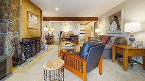Ein gemütliches Wohnzimmer mit Kamin, Essbereich und einer Küche im Hintergrund.