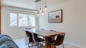 A dining area with a wooden table, black chairs, and a hanging light fixture.