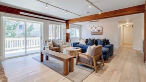 A spacious living area with a large window, a wooden ceiling, and a blue sofa.
