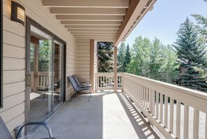Ein überdachter Balkon mit Geländer, Glastür und zwei Stühlen.