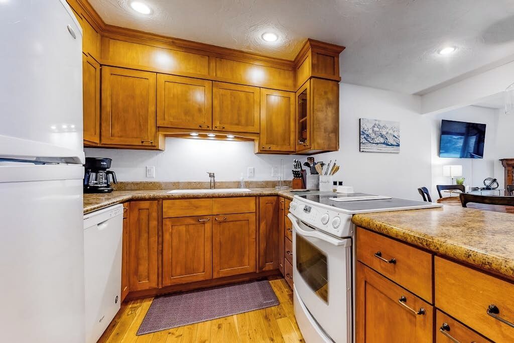 A kitchen with wooden cabinets, a white refrigerator, a stove, and a sink.