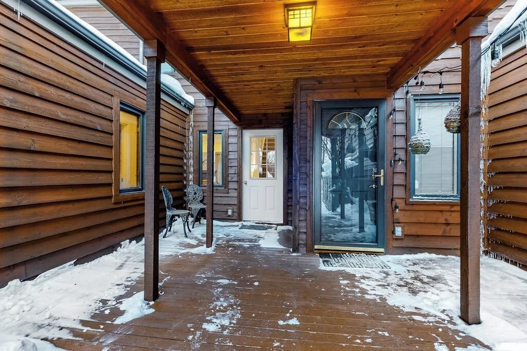 A wooden cabin with a covered porch, a glass door, and a bench.