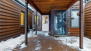 Eine Holzhütte mit überdachter Veranda, einer Glastür und einer Sitzbank.