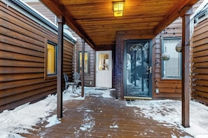 Eine Holzhütte mit überdachter Veranda, einer Glastür und einer Sitzbank.