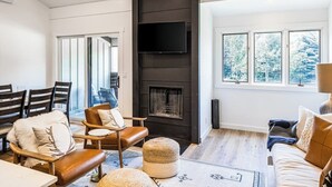 A modern living room with a fireplace, comfortable seating, and large windows. - Gorgeous, modern mountain view condo with deck & great kitchen (Wilson)