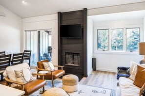 Ein modernes Wohnzimmer mit Kamin, gemütlicher Sitzgelegenheit und großen Fenstern.
