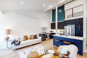 Ein modernes Wohnzimmer mit Sofa, Couchtisch und Essbereich mit Stühlen.