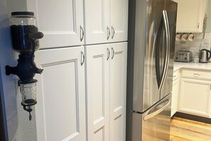 Eine Küche mit weißen Schränken, einem Edelstahlkühlschrank, einem Toaster und einer Kaffeemaschine.