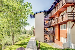 Ein modernes Gebäude mit einem Holzbalkon, einem Weg und einem Baum.