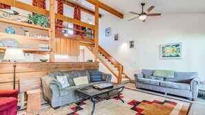 A living room with a sofa, a coffee table, a staircase, and a ceiling fan. - Lovely condo with fireplace, skiing, balcony, full kitchen & washer/dryer (Wilson)