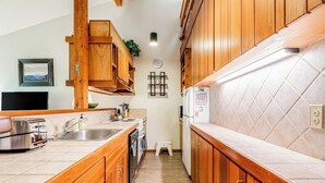 A narrow kitchen with wooden cabinets, a built-in oven, and a refrigerator. - Lovely condo with fireplace, skiing, balcony, full kitchen & washer/dryer (Wilson)