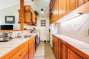 A narrow kitchen with wooden cabinets, a built-in oven, and a refrigerator. - Lovely condo with fireplace, skiing, balcony, full kitchen & washer/dryer (Wilson)