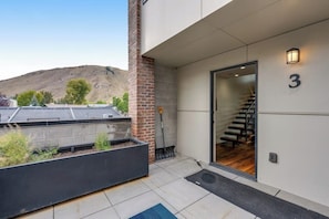 Ein moderner Hauseingang mit Glastür, einer sichtbaren Treppe und der Zahl 3 an der Wand.