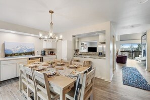 Une cuisine moderne avec un coin repas, un plancher en bois et un lustre.