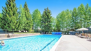 A rectangular swimming pool with clear blue water, surrounded by a concrete deck.
