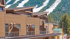 Ein Holzhaus mit Balkonen, im Hintergrund eine Skipiste und ein Schild mit der Aufschrift 'Jackson Hole'.