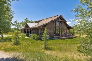 A log cabin with a porch, surrounded by greenery. - Impressive mtn-view home near national parks with deck, fireplace, & streaming (Jackson)