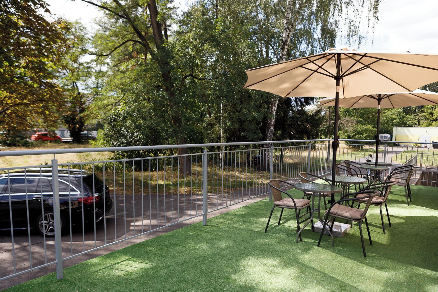 A patio area with artificial grass, outdoor furniture, and a large umbrella.