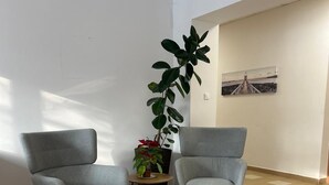 Una habitación con dos sillones grises, una planta en maceta, una mesita y un cuadro en la pared.