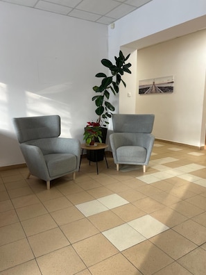 A room with two grey armchairs, a potted plant, a small table, and a painting on the wall. - ALLIANCE - M (Warsaw)