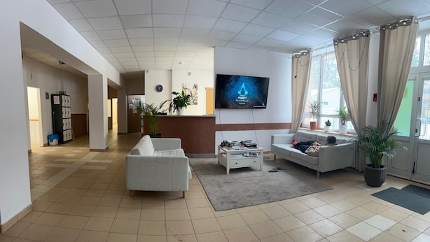 Amplia sala de estar con sofá, una mesa de centro y un televisor montado en la pared.