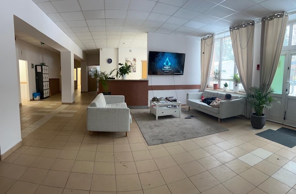 A spacious living area with a sofa, a coffee table, and a TV mounted on the wall. - ALLIANCE - M (Warsaw)