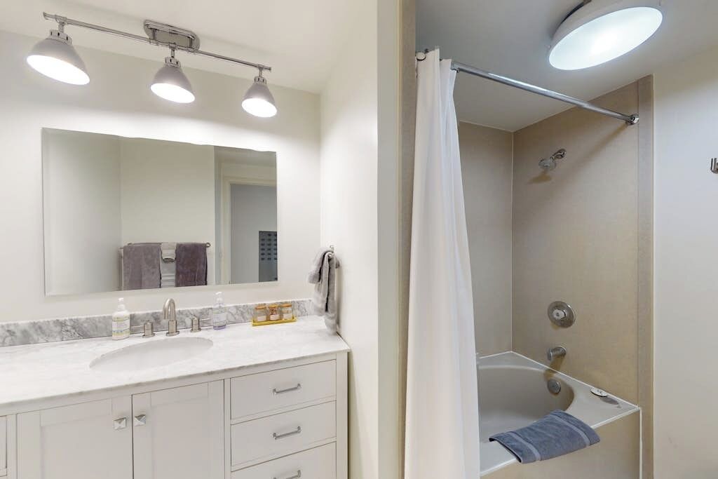 A bathroom with a sink, mirror, and shower.
