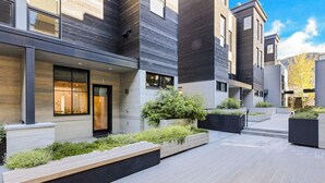 A modern building with a courtyard, featuring a mix of wooden and concrete elements, and a variety of plants. - Luxury townhouse w/ hot tub, great views & incredible location (Jackson)