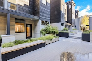 A modern building with a courtyard, featuring a mix of wooden and concrete elements, and a variety of plants. - Luxury townhouse w/ hot tub, great views & incredible location (Jackson)