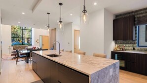 A modern kitchen with a large island, pendant lighting, and dark cabinetry. - Luxury townhouse w/ hot tub, great views & incredible location (Jackson)