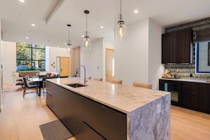 A modern kitchen with a large island, pendant lighting, and dark cabinetry. - Luxury townhouse w/ hot tub, great views & incredible location (Jackson)