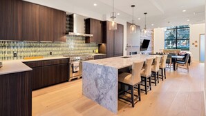 A modern kitchen with a marble island, dark wood cabinetry, and pendant lighting. - Luxury townhouse w/ hot tub, great views & incredible location (Jackson)