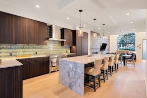 A modern kitchen with a marble island, dark wood cabinetry, and pendant lighting. - Luxury townhouse w/ hot tub, great views & incredible location (Jackson)