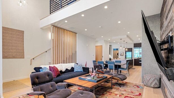 A spacious living area with a sofa, ottoman, and coffee table, a staircase, and a fireplace. - Luxury townhouse w/ hot tub, great views & incredible location (Jackson)