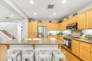 A modern kitchen with granite countertops, stainless steel appliances, and wooden cabinets.