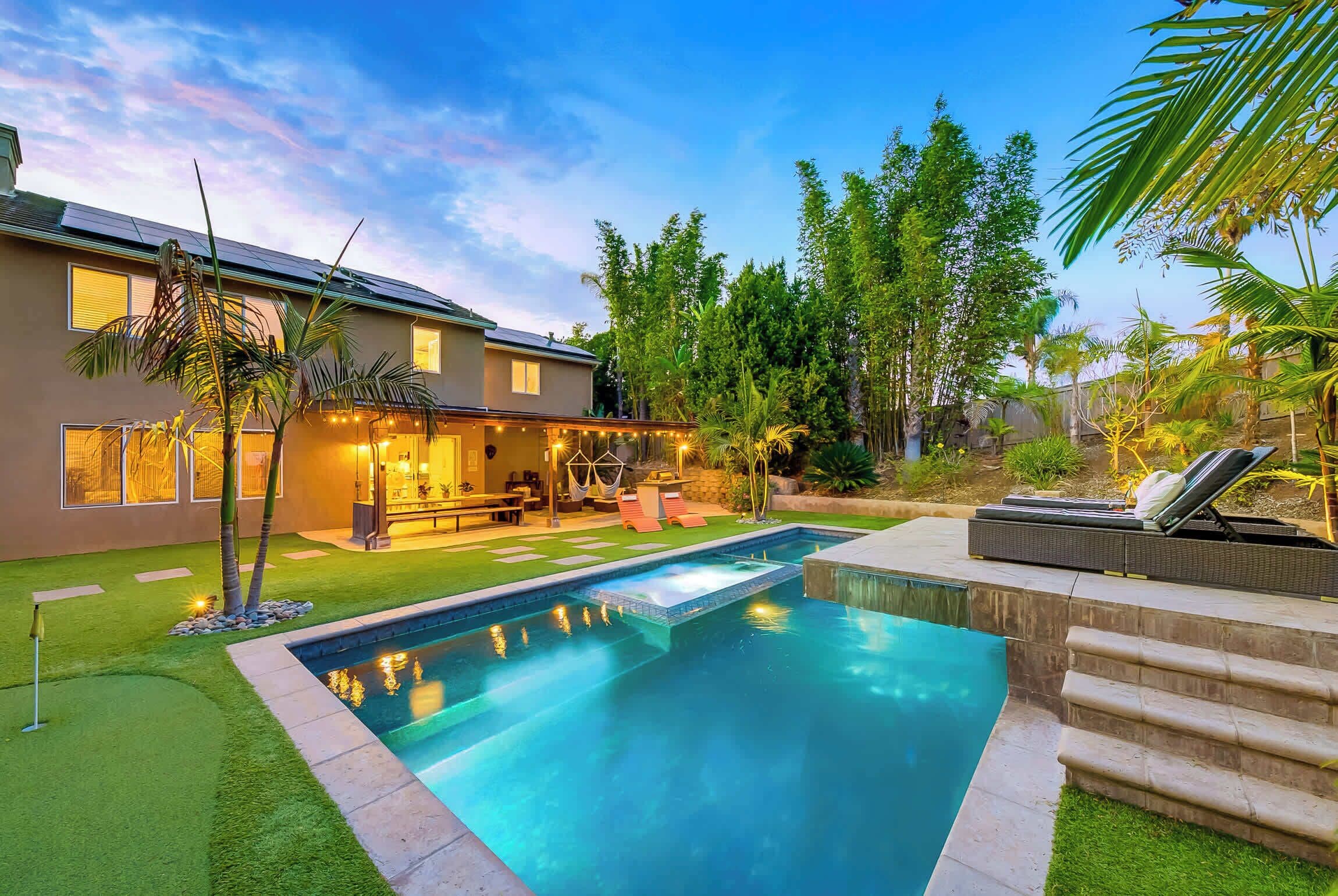 A modern house with a swimming pool, outdoor seating, and lush greenery.