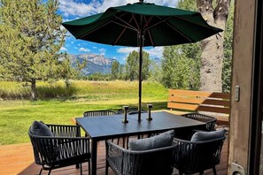 Eine Terrasse im Freien mit Tisch und Stühlen, einer Holzbank und einem grünen Sonnenschirm.