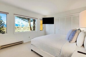Ein Schlafzimmer mit einem Bett, einem an der Wand montierten Fernseher und einem Fenster mit Blick auf die Berge.